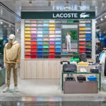 Lacoste store display with colorful polo shirts, mannequins, and accessories. Title: