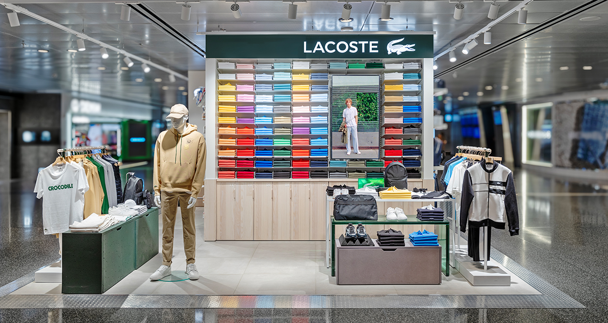 Lacoste store display with colorful polo shirts, mannequins, and accessories. Title: