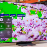 Modern smart TV displaying vibrant floral image with on-screen settings menu in a showroom